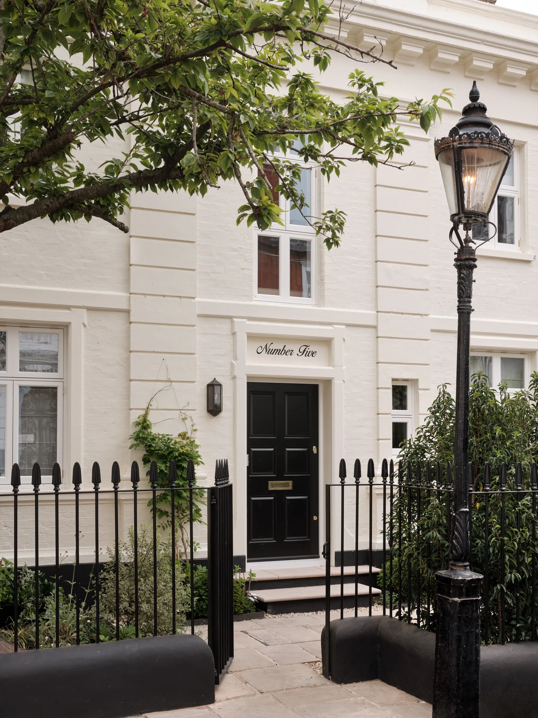 White stucco façade with black front door, railings and period street lamp