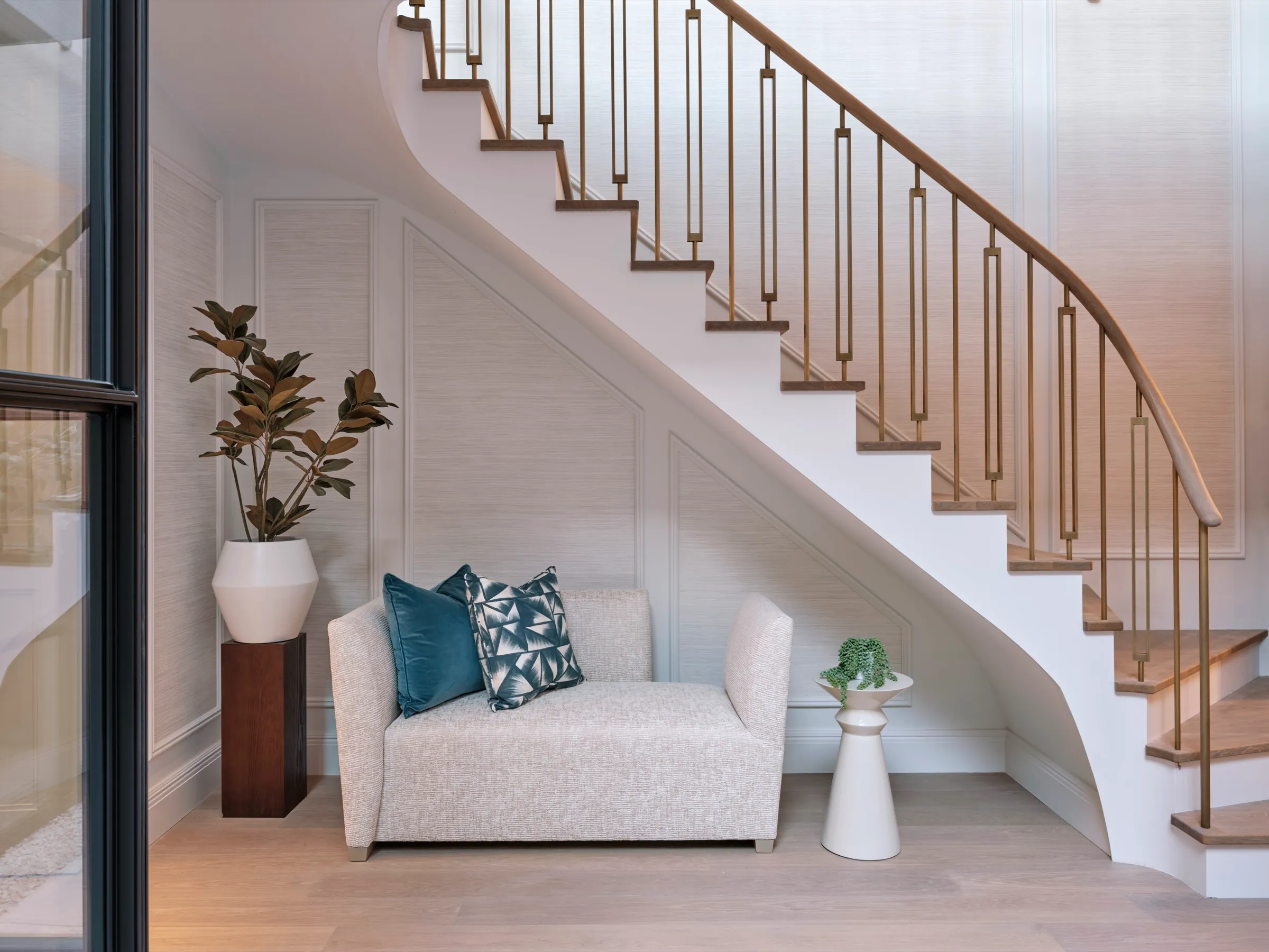 Curved staircase with brass balustrade above a seating niche