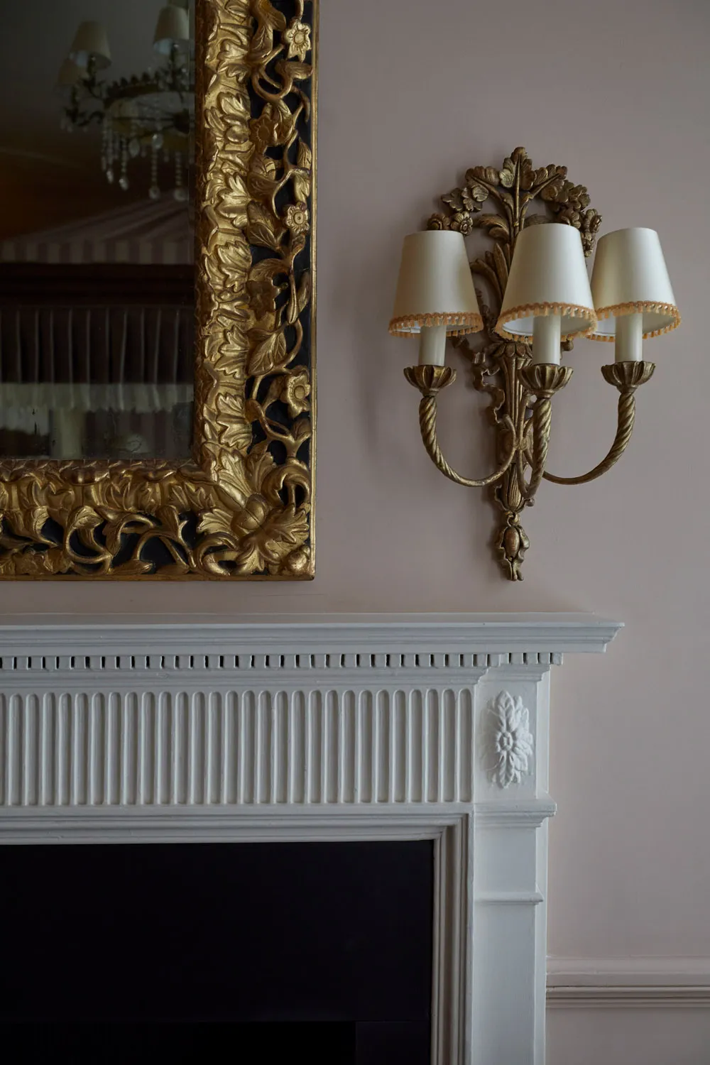 Period fireplace with gilt mirror and wall sconce