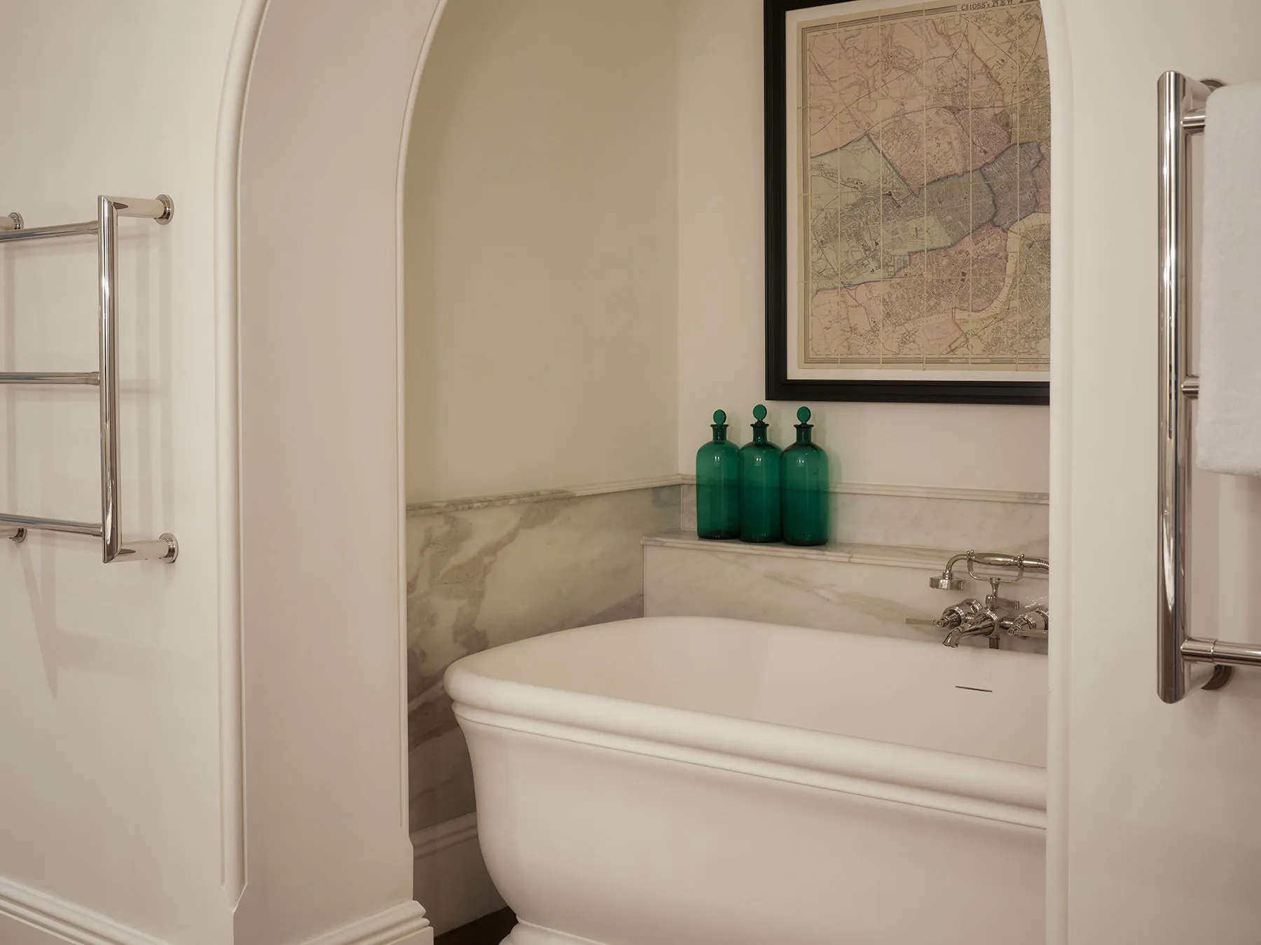 Roll-top bath in an arched, marble-lined alcove