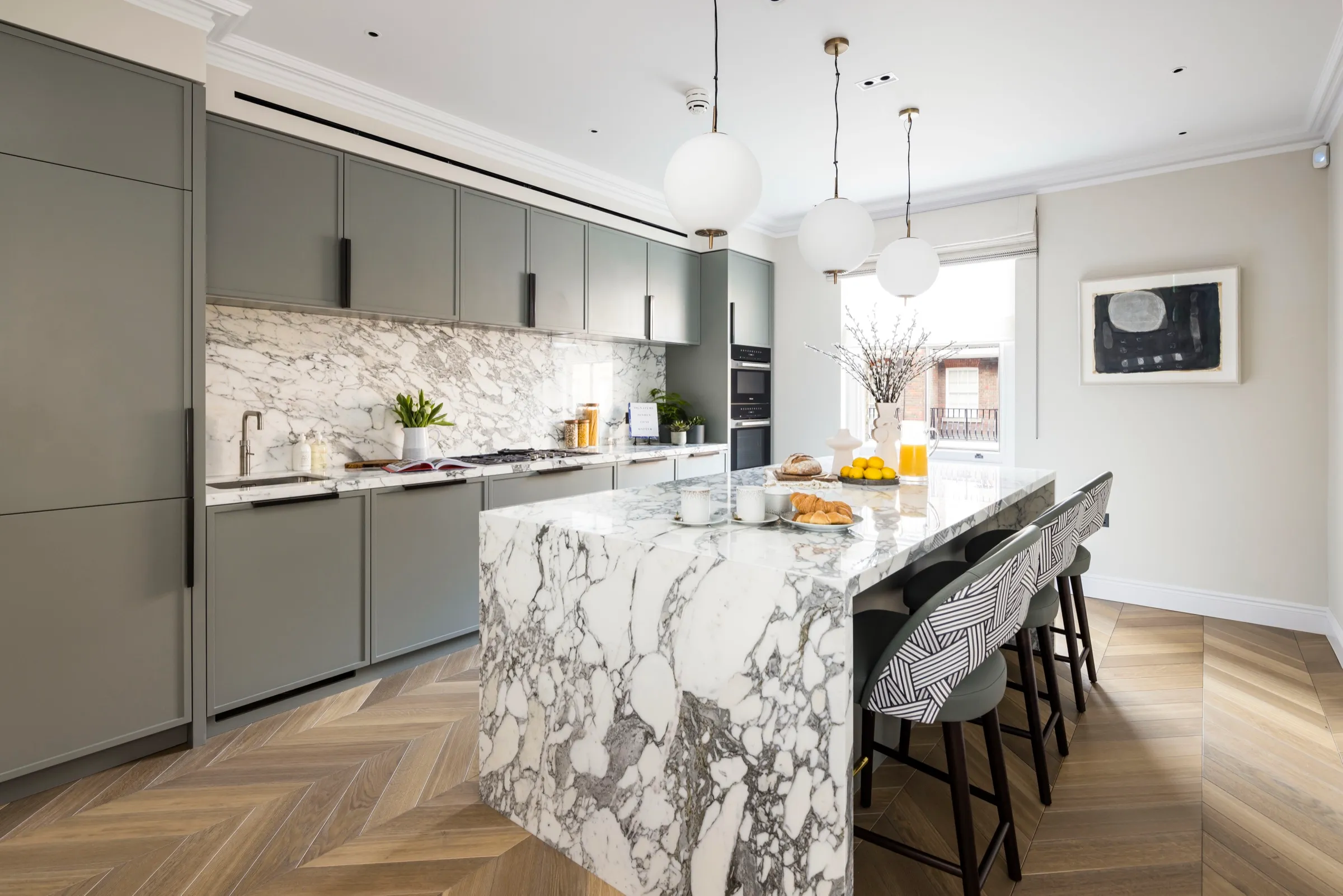 Kitchen with grey cabinetry and waterfall marble island