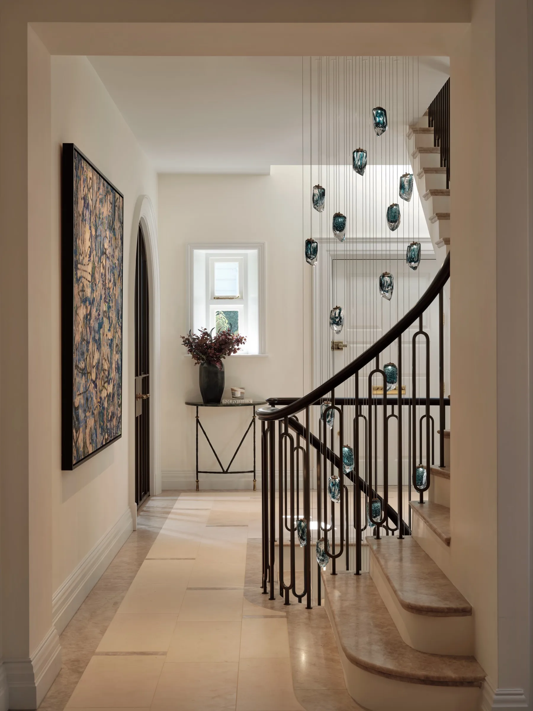 Curved staircase with metal balustrade and glass pendant lights