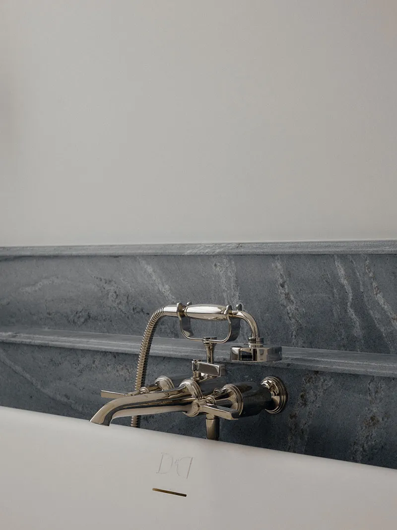 Brass bath taps against a marble upstand