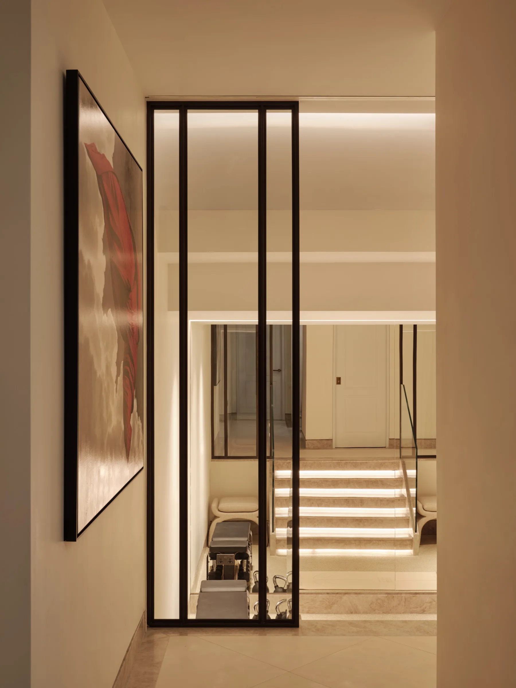 Steel-framed glazed screen beside a lit staircase