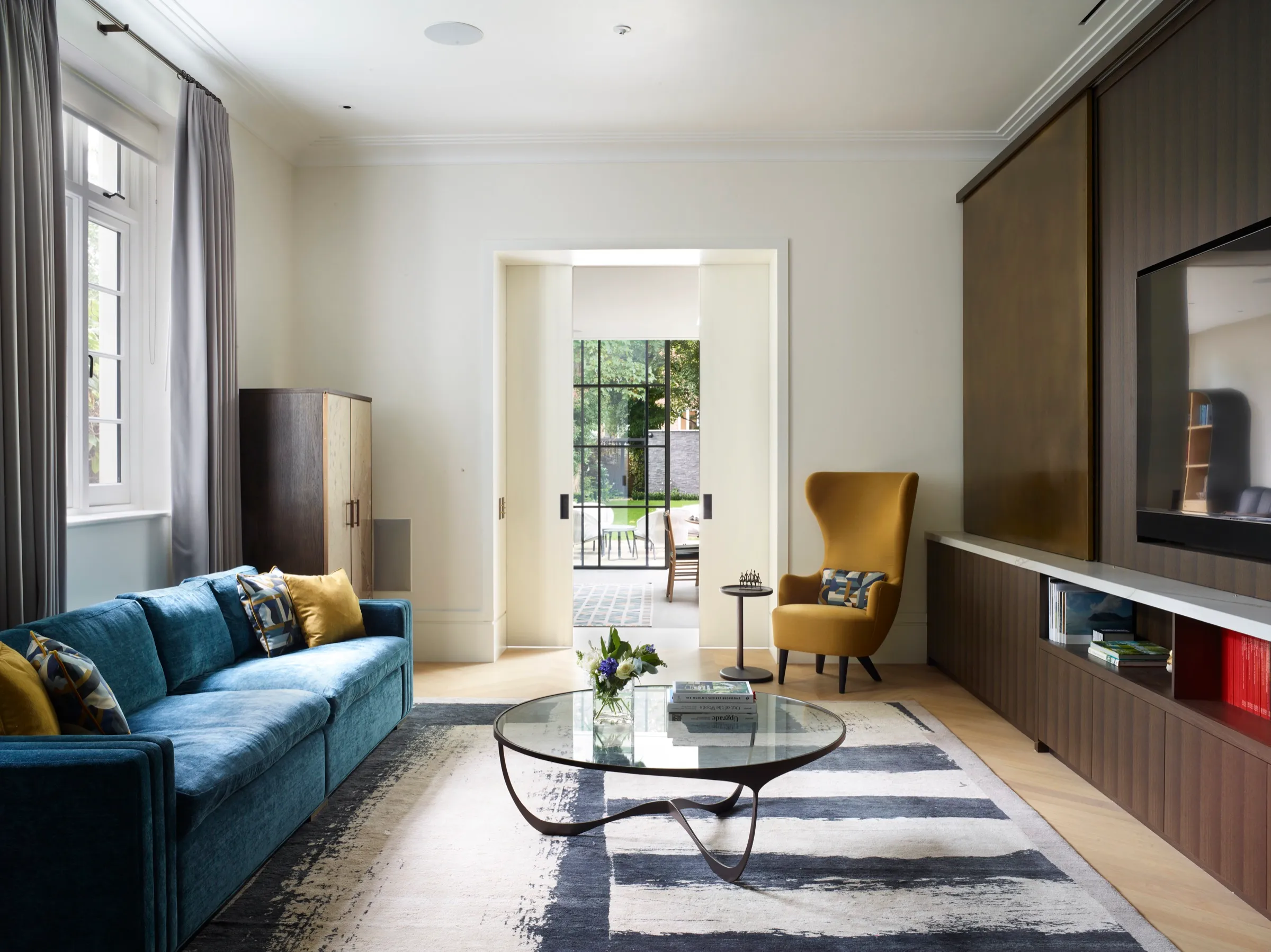 Living room with bronze media wall and doors through to the garden