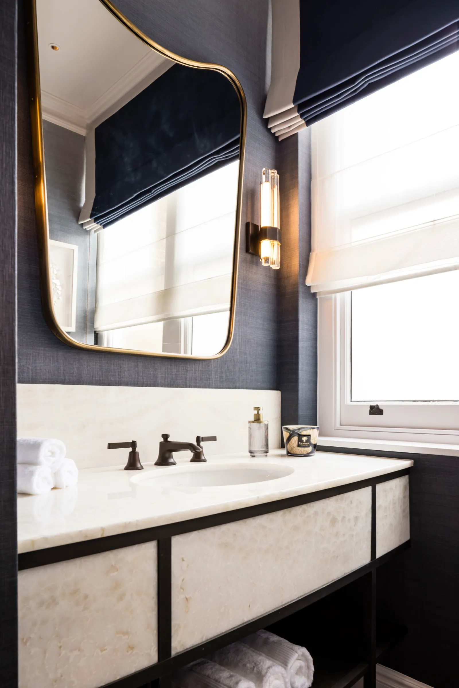 Vanity with stone top and brass-framed mirror