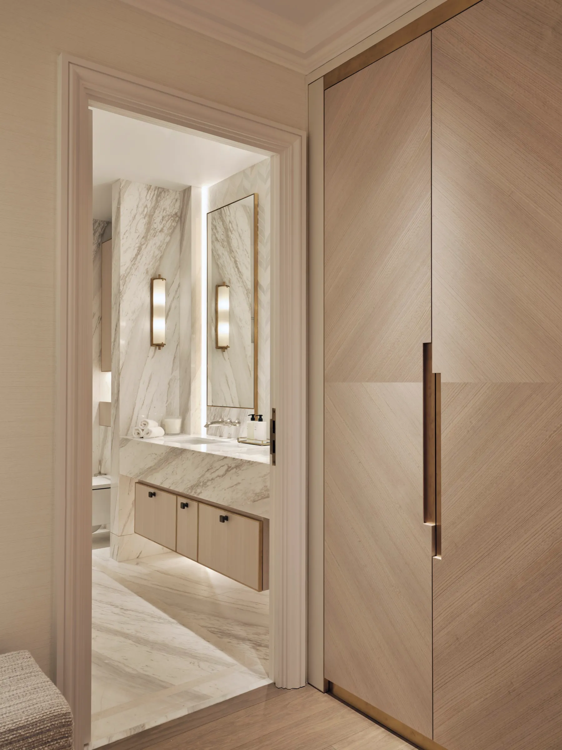 Timber-veneered wardrobe beside a marble bathroom