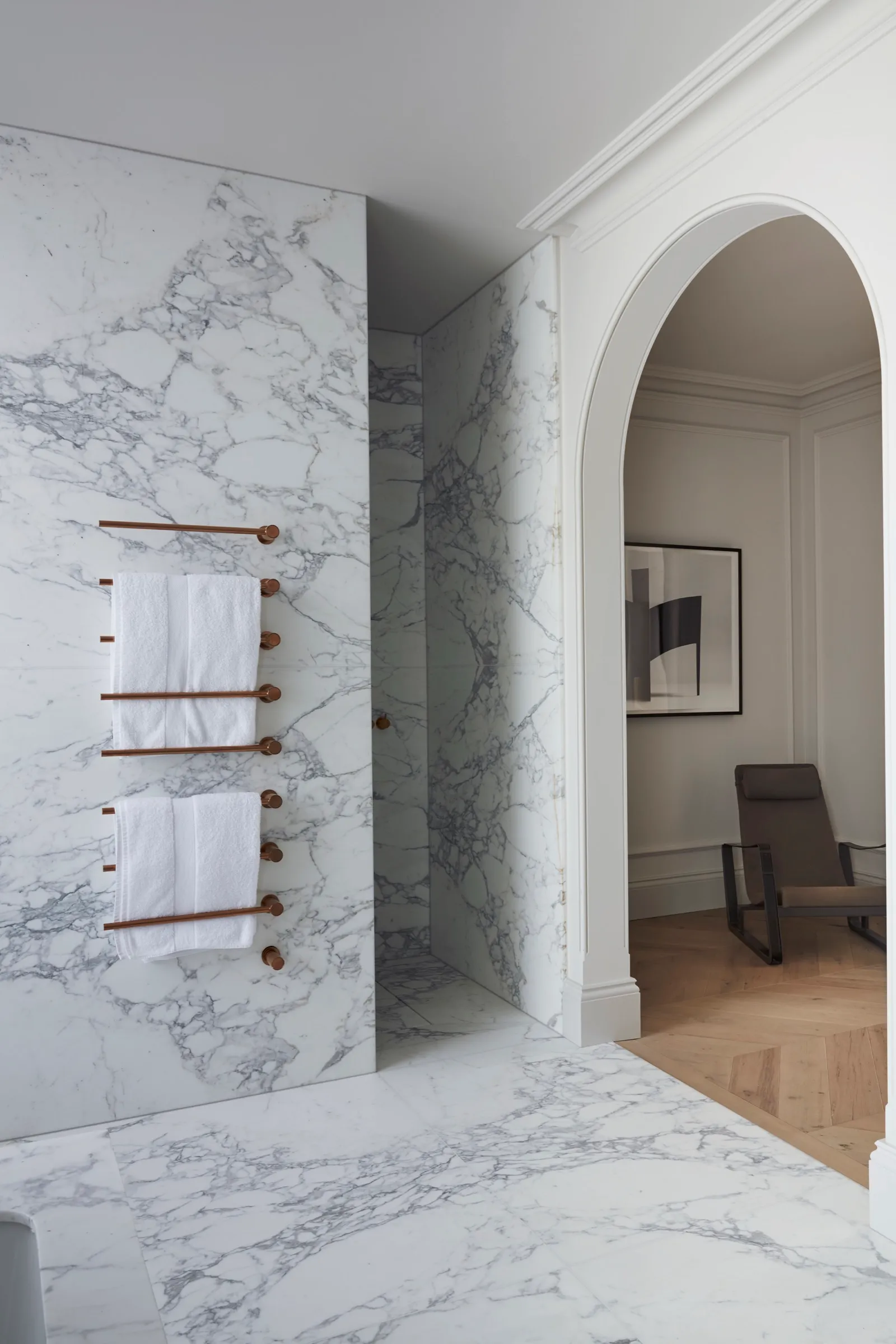 Marble-lined shower with arched doorway