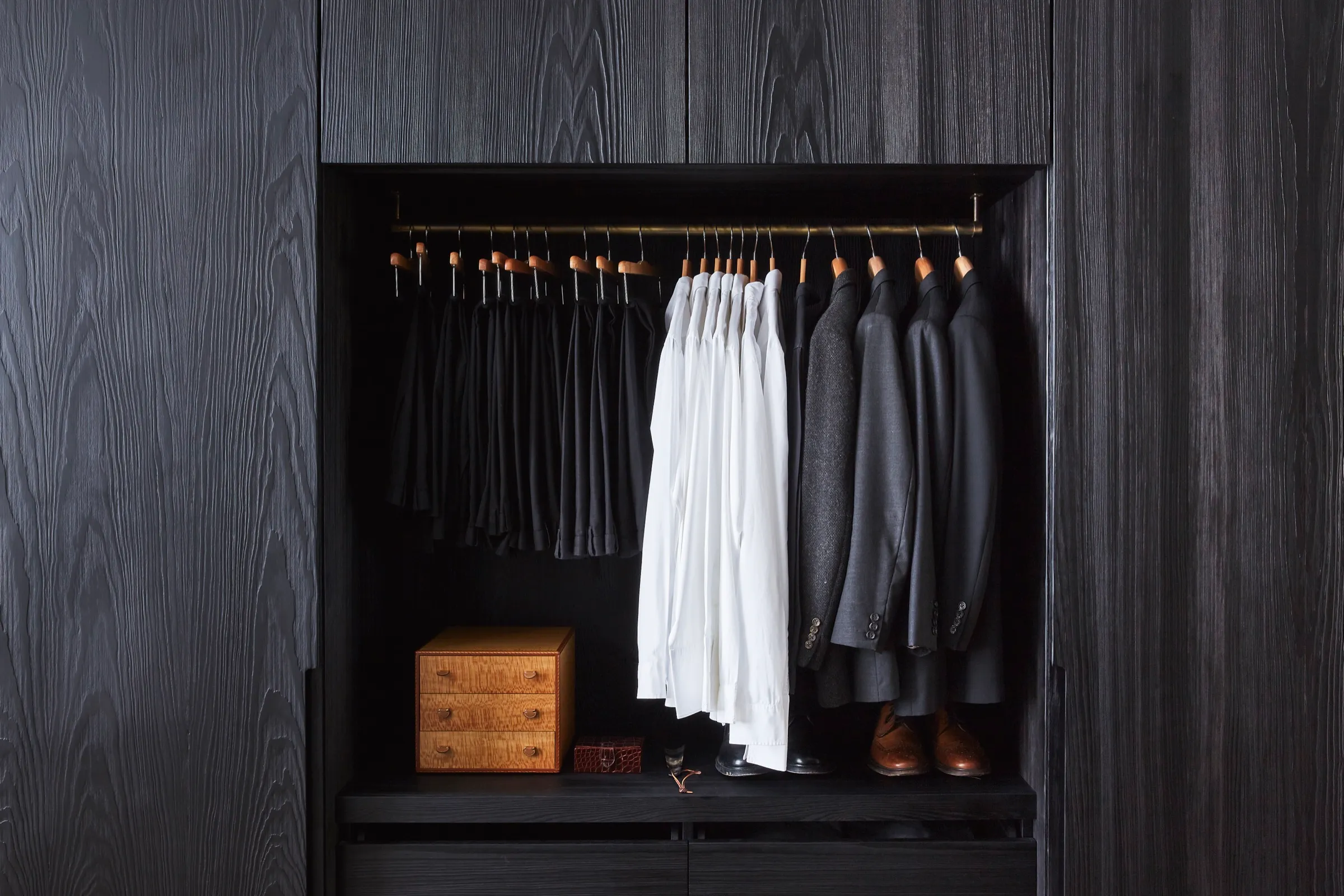 Dark timber wardrobe joinery with brass hanging rail